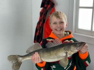 boy with walleye in fish house border view lodge 022722