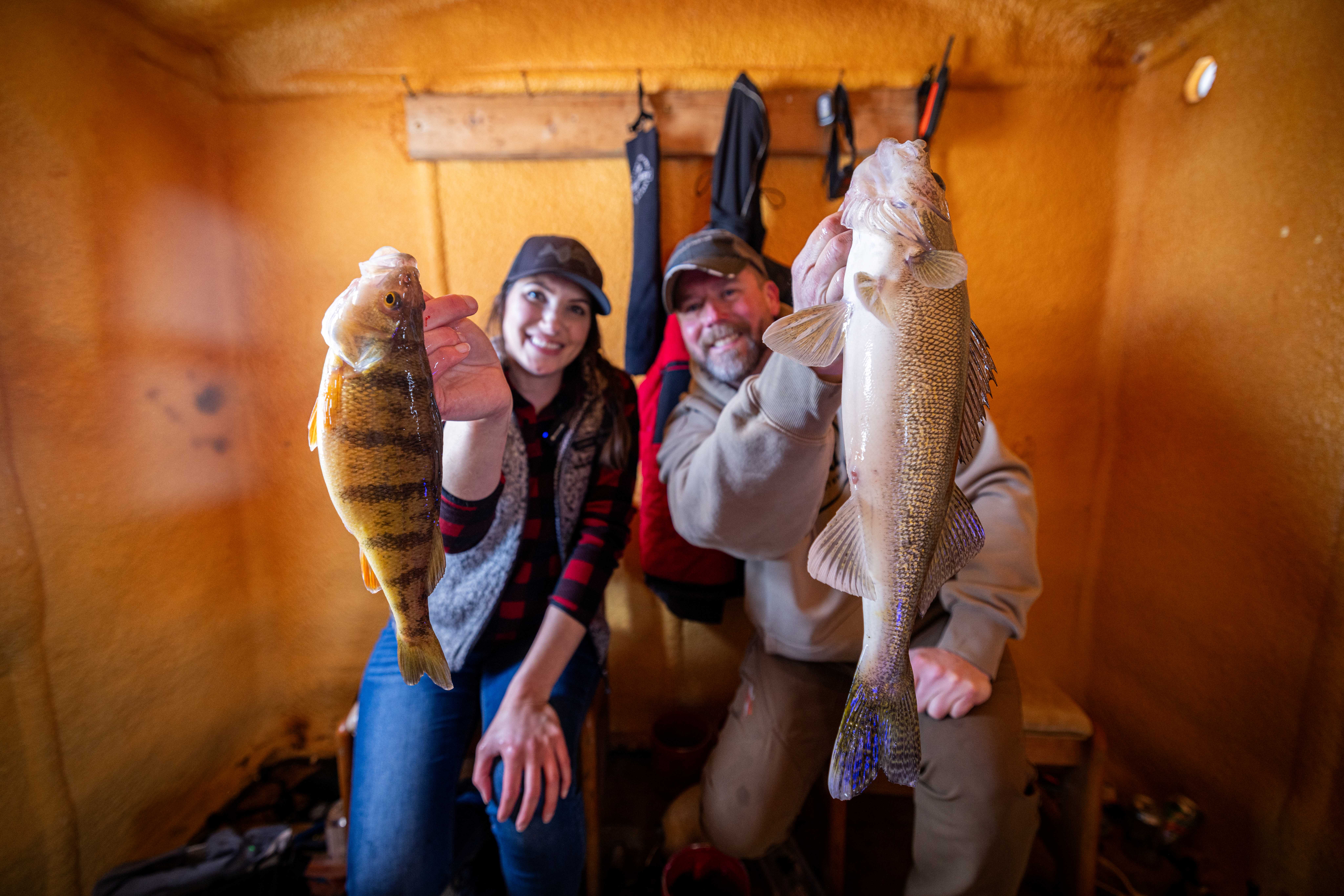 Jen Pudenz and Bret Amundson with a jumbo perch and walleye inside a Lake of the Woods MN fish house, full service ice fishing