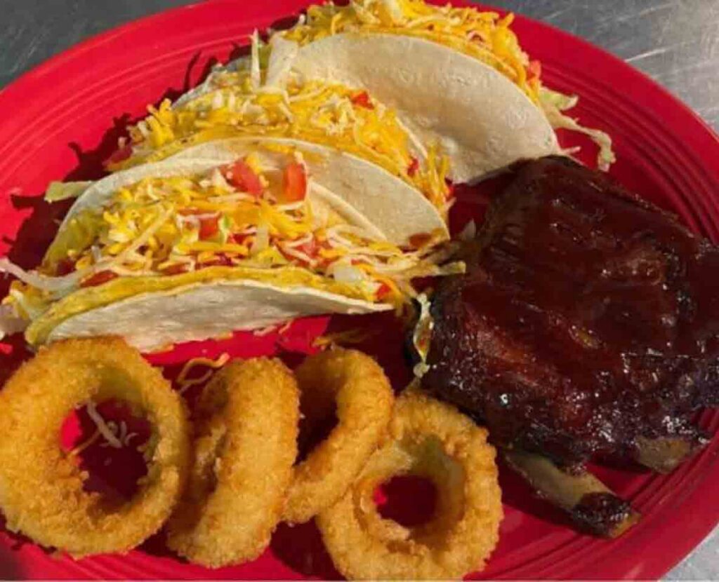 Tacos and barbqued ribs with hand-battered onion rings on a bright red plate