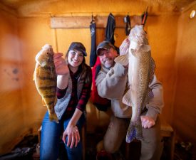 Jen Pudenz and Bret Amundson with a jumbo perch and walleye inside a Lake of the Woods MN fish house, full service ice fishing
